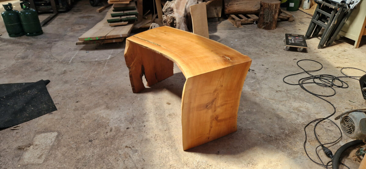 Découvrez ce bureau en merisier artisanal, né d'un arbre courbé par le temps, offrant un design naturel unique. Chaque teinte orangée raconte l'union avec le cerisier, pour une histoire qui a traversé les siècles. Avec des fissures mises en valeur par le métal doré, cette pièce poinçonnée est une véritable tranche de vie intemporelle et un ajout exceptionnel à tout espace de travail.