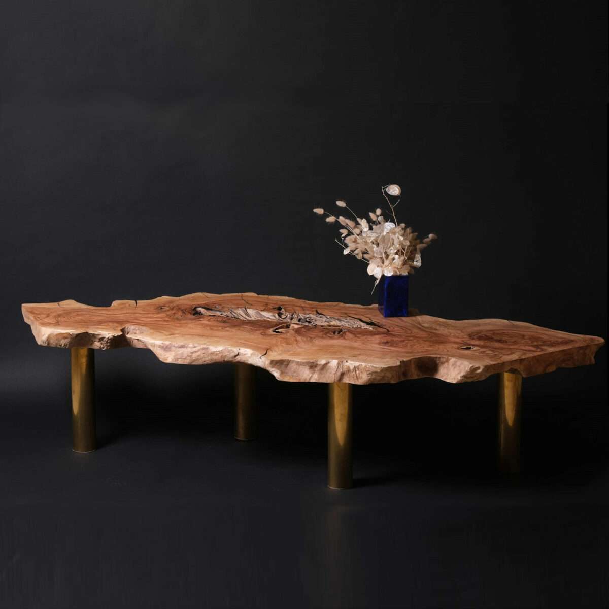 Table basse en olivier aux dimensions exceptionnelles, évoquant la beauté organique avec ses courbes gracieuses et veines uniques. Incrustations en laiton et ébène enrichissent son esthétique intemporelle et contemporaine. Pieds en laiton ajoutant élégance et stature